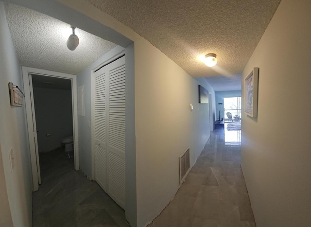 hall featuring visible vents and a textured ceiling
