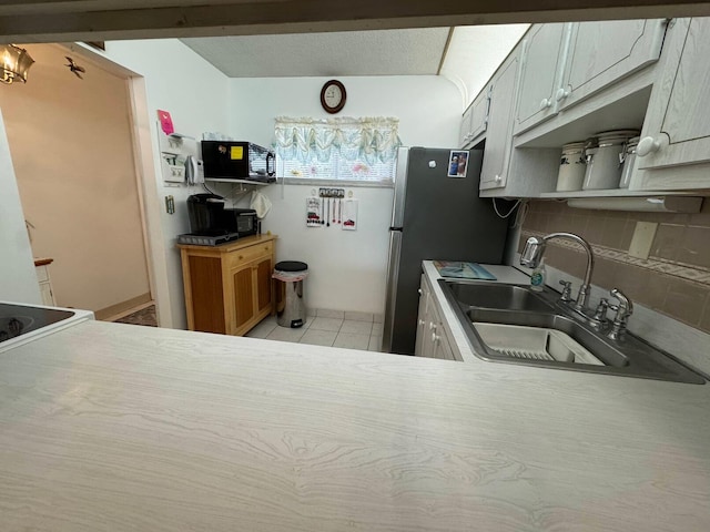 kitchen featuring stainless steel fridge, light tile patterned flooring, sink, and tasteful backsplash