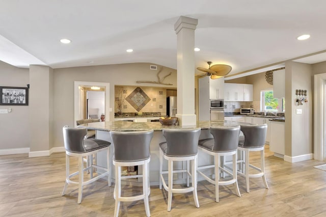 kitchen featuring light wood-type flooring, a kitchen island, tasteful backsplash, white cabinetry, and stainless steel appliances