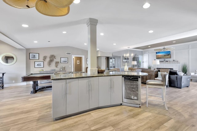 kitchen with billiards, light hardwood / wood-style flooring, beverage cooler, dark stone countertops, and lofted ceiling