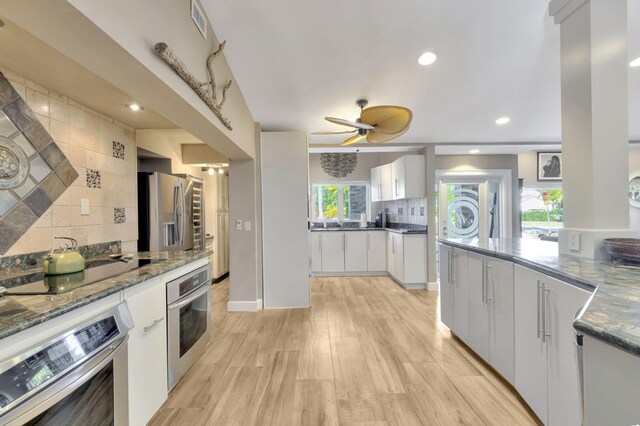 kitchen featuring appliances with stainless steel finishes, light hardwood / wood-style floors, decorative backsplash, white cabinets, and ceiling fan