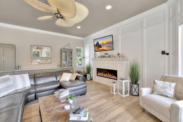 living room with ceiling fan, light wood-type flooring, and ornamental molding