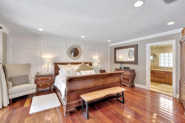 bedroom featuring hardwood / wood-style flooring, ornamental molding, and ensuite bathroom