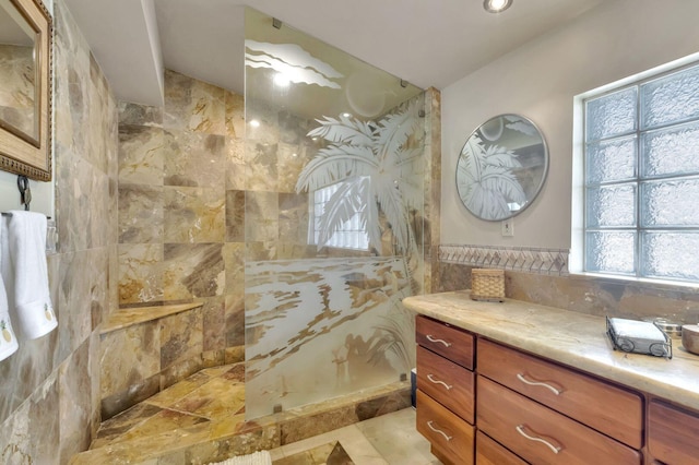 bathroom with tile patterned floors, a tile shower, plenty of natural light, and vanity