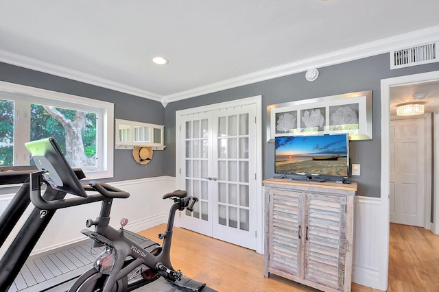 exercise area featuring light wood-type flooring, crown molding, and french doors