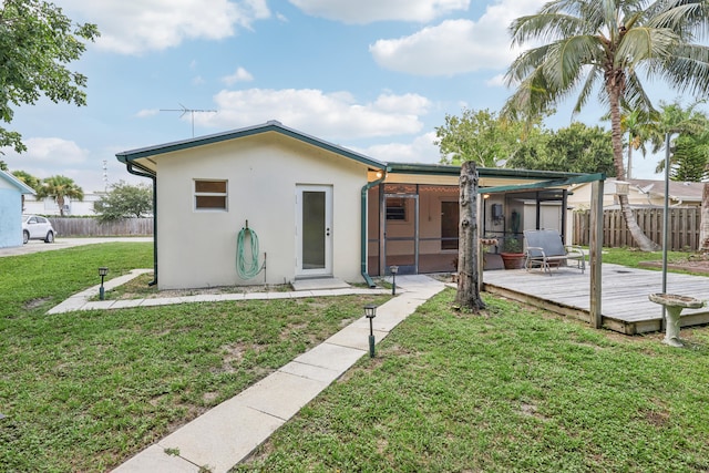 rear view of property with a deck, a lawn, and an outdoor structure