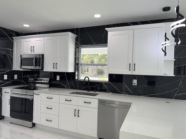 kitchen with appliances with stainless steel finishes, sink, decorative light fixtures, white cabinets, and backsplash