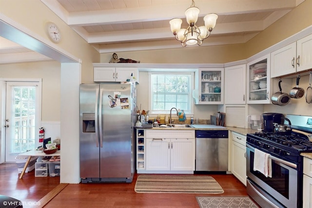 kitchen featuring appliances with stainless steel finishes, plenty of natural light, sink, white cabinetry, and hanging light fixtures