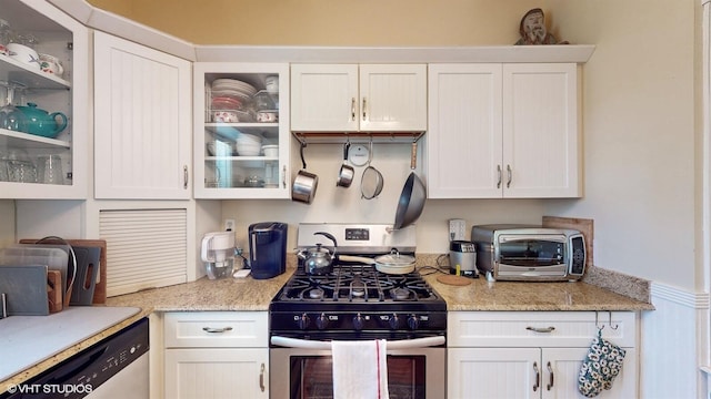 kitchen with light stone counters, white cabinets, and stainless steel appliances