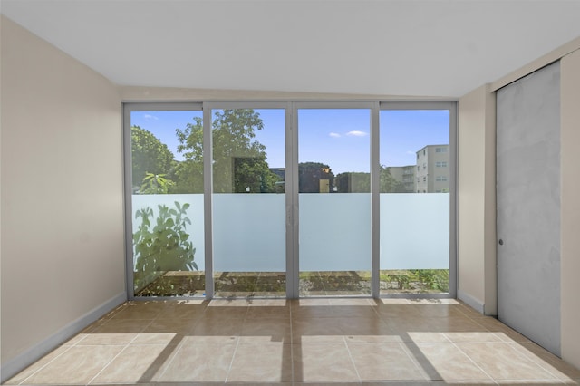 tiled spare room with expansive windows and baseboards