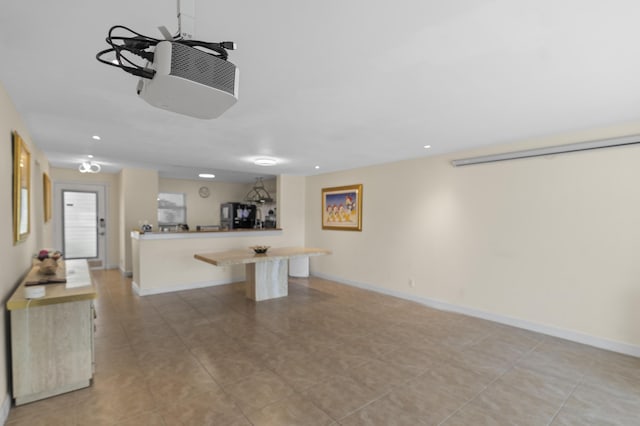 kitchen featuring a breakfast bar, recessed lighting, light countertops, a peninsula, and baseboards