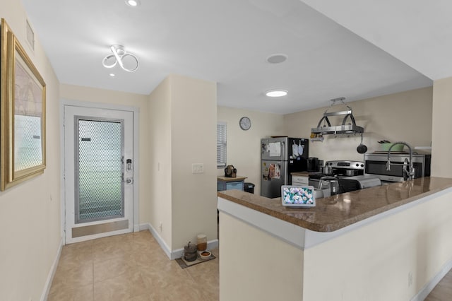 kitchen featuring light tile patterned flooring, stainless steel appliances, a peninsula, visible vents, and baseboards