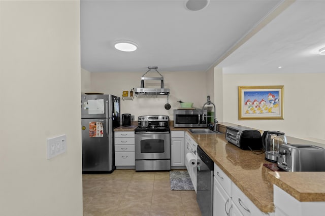 kitchen featuring light tile patterned floors, white cabinets, wall chimney exhaust hood, stainless steel appliances, and a sink