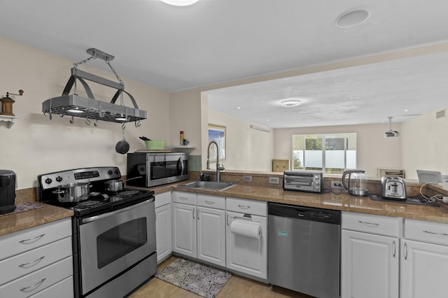 kitchen featuring stainless steel appliances, a toaster, white cabinets, and a sink