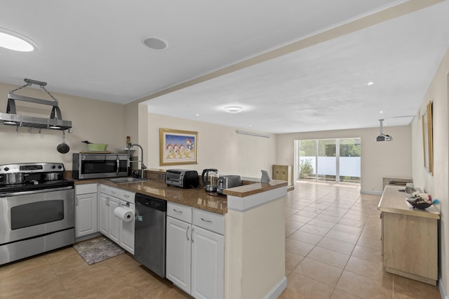 kitchen featuring light tile patterned flooring, stainless steel appliances, a peninsula, a sink, and open floor plan