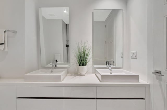 bathroom with toilet and double sink vanity