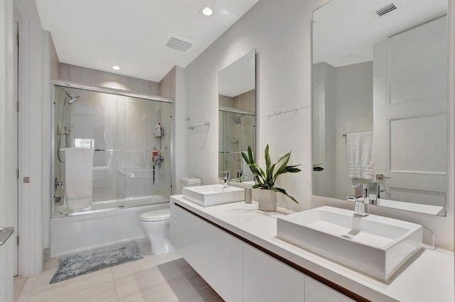 full bathroom with shower / bath combination with glass door, toilet, tile patterned flooring, and double vanity