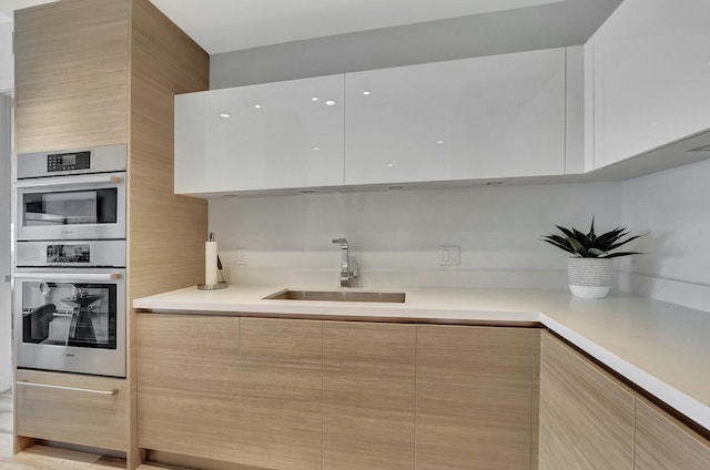 kitchen with sink, stainless steel double oven, and light brown cabinets