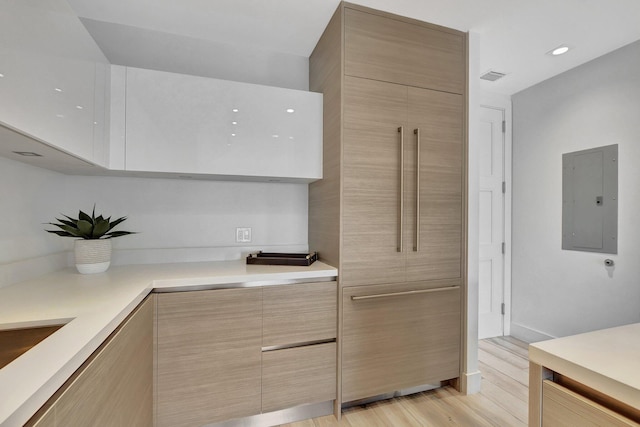 kitchen with light brown cabinets, light wood-type flooring, and electric panel