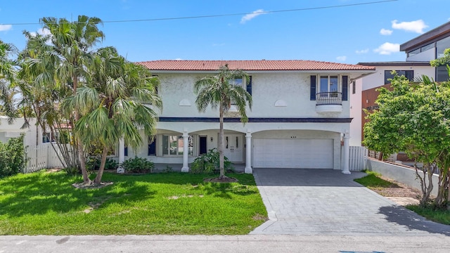 mediterranean / spanish home with a balcony, a garage, and a front lawn