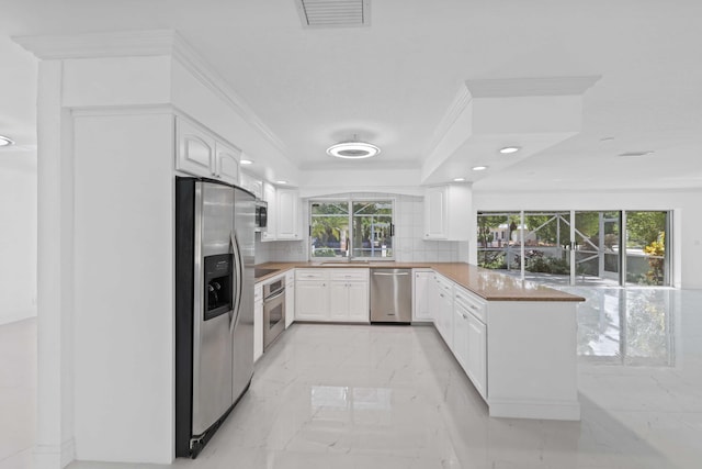 kitchen with white cabinetry, kitchen peninsula, backsplash, stainless steel appliances, and plenty of natural light