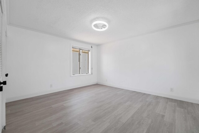 spare room featuring a textured ceiling and light hardwood / wood-style flooring