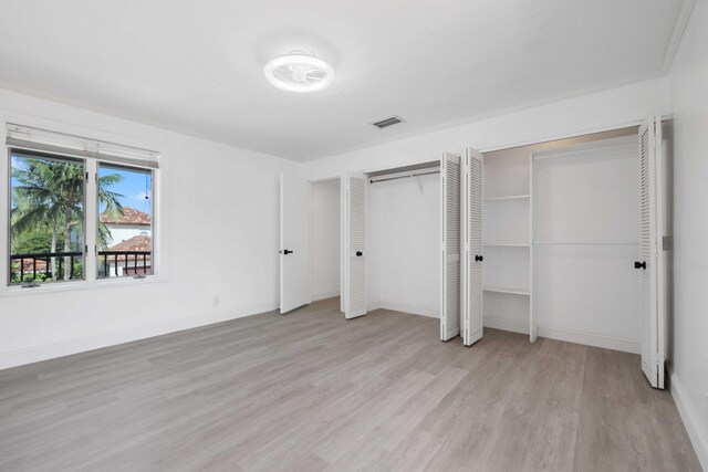 unfurnished bedroom with light wood-type flooring and two closets