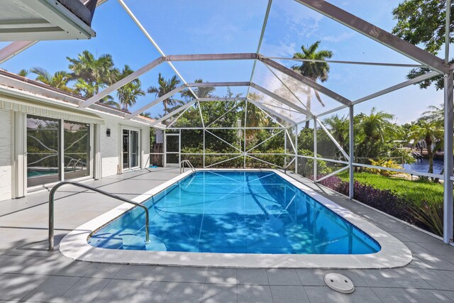 view of pool with glass enclosure and a patio