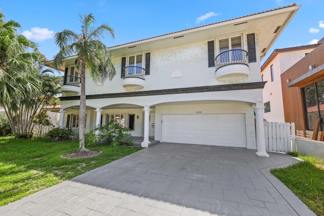 mediterranean / spanish home featuring a front yard, a balcony, and a garage