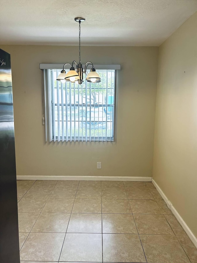 unfurnished dining area featuring an inviting chandelier, light tile patterned flooring, and a healthy amount of sunlight