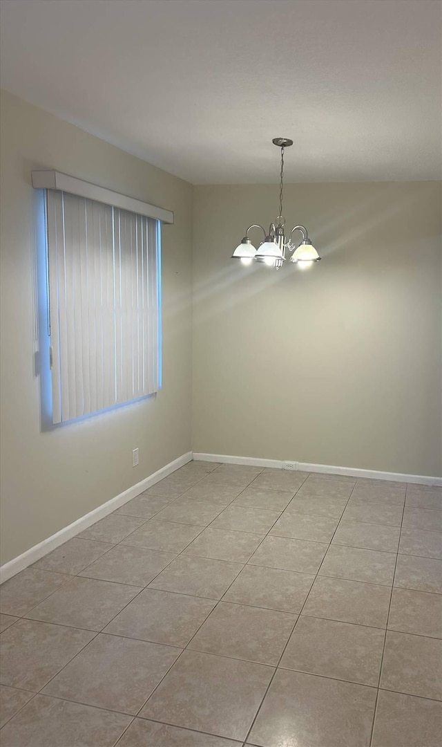 empty room featuring an inviting chandelier and light tile patterned floors