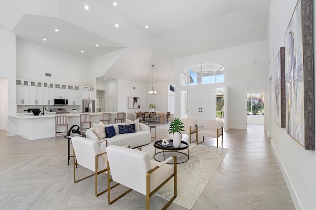 living room with light parquet flooring, a high ceiling, and a notable chandelier