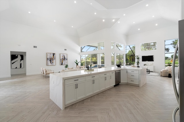 kitchen with a towering ceiling, light parquet floors, white cabinetry, and light stone countertops