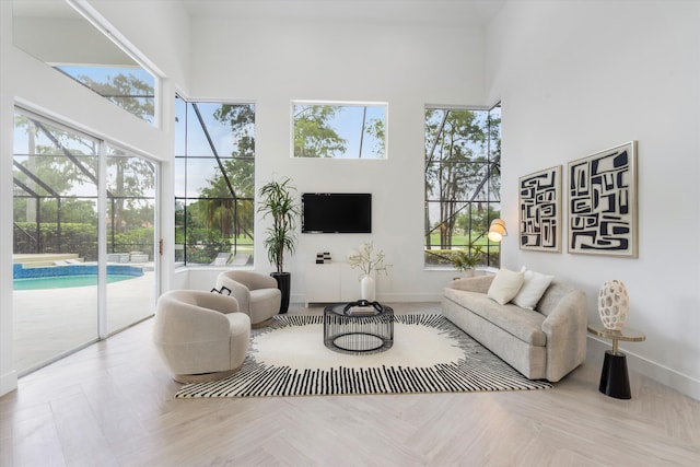 living room with a towering ceiling and light parquet floors