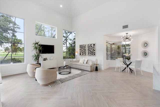 living room featuring a towering ceiling, light parquet flooring, and a chandelier