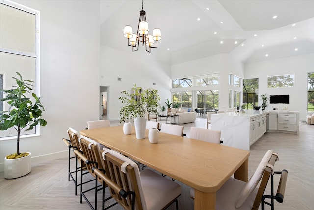 dining area featuring light parquet flooring, a chandelier, and a high ceiling