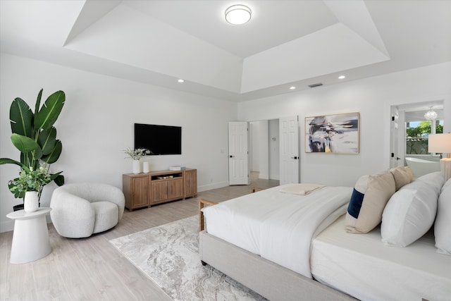 bedroom with a tray ceiling and light hardwood / wood-style flooring