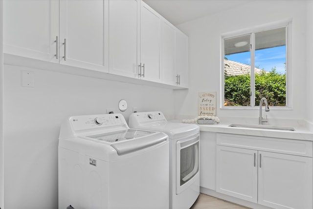 laundry room featuring light wood-type flooring, cabinets, washing machine and clothes dryer, and sink