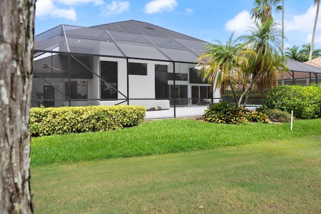 back of property featuring a yard and glass enclosure