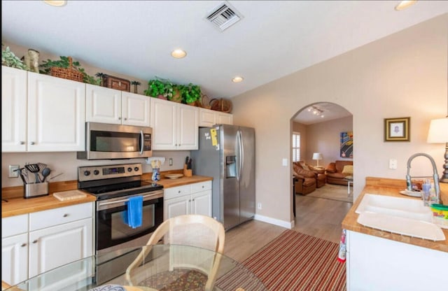 kitchen with sink, white cabinetry, appliances with stainless steel finishes, and light hardwood / wood-style floors