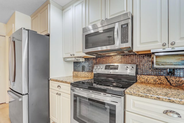 kitchen with light stone counters, decorative backsplash, stainless steel appliances, and white cabinetry