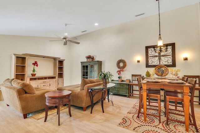 living room with a towering ceiling, ceiling fan, and light wood-type flooring