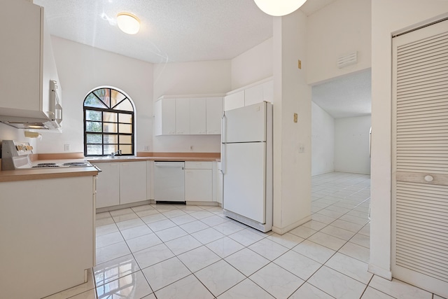 kitchen with white appliances, sink, a textured ceiling, light tile patterned flooring, and white cabinetry