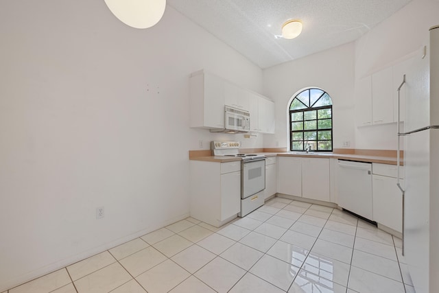 kitchen featuring white cabinetry, white appliances, sink, a textured ceiling, and light tile patterned floors