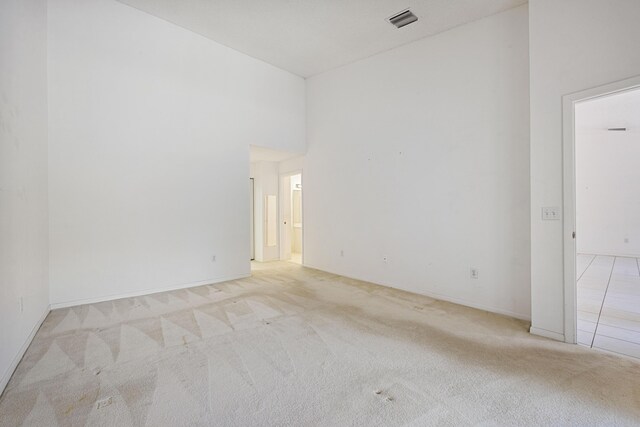 unfurnished room with a towering ceiling and light colored carpet