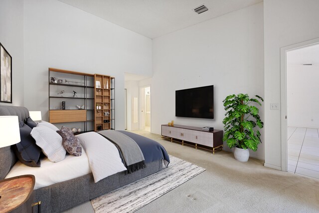 bedroom featuring light carpet, connected bathroom, and a high ceiling