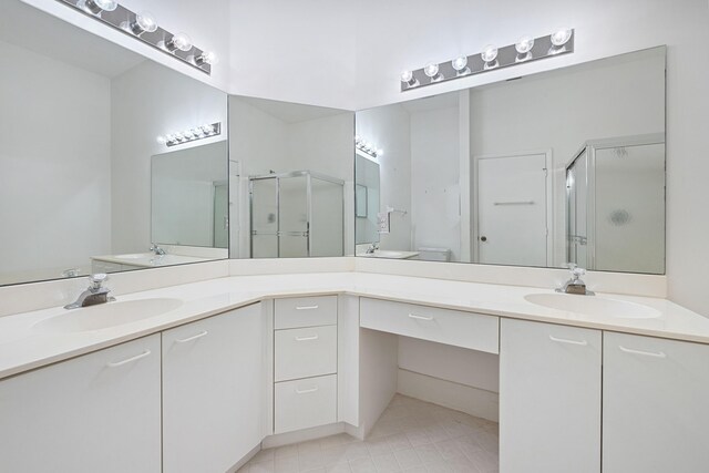 bathroom featuring a shower with shower door, tile patterned flooring, and double vanity