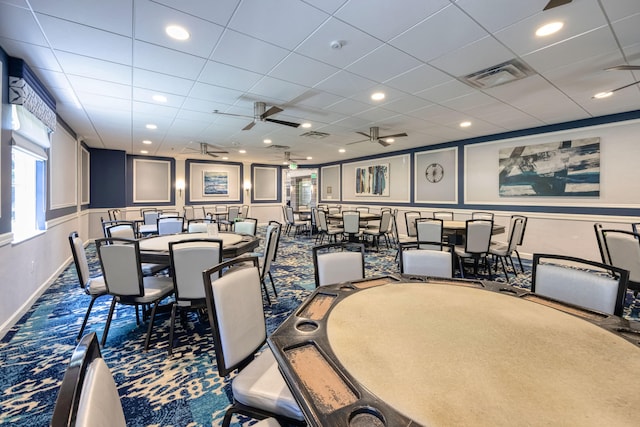 carpeted dining area featuring ceiling fan and a paneled ceiling