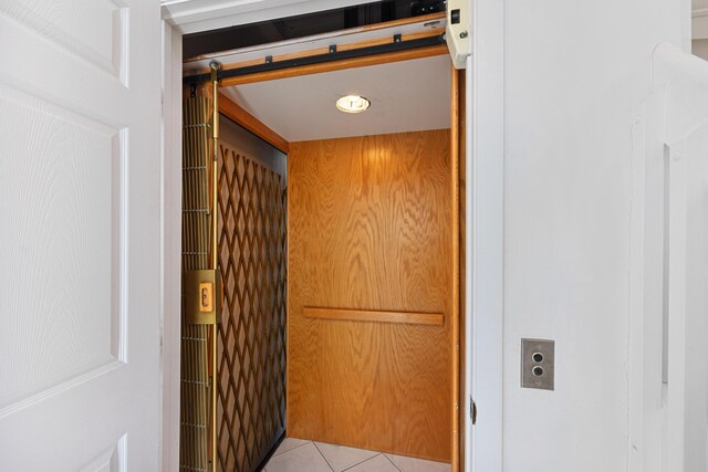 details featuring tile patterned flooring, wooden walls, elevator, and a barn door