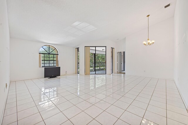 tiled spare room with a notable chandelier, lofted ceiling, and a healthy amount of sunlight